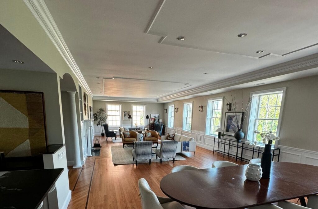 Painter rolling fresh color onto living room wall in occupied Hopkinton home
