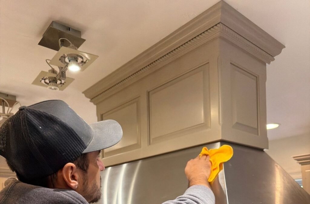 Lucena Painting painter wiping a freshly painted grey cabinet crown, part of cabinet painting work in Franklin, MA
