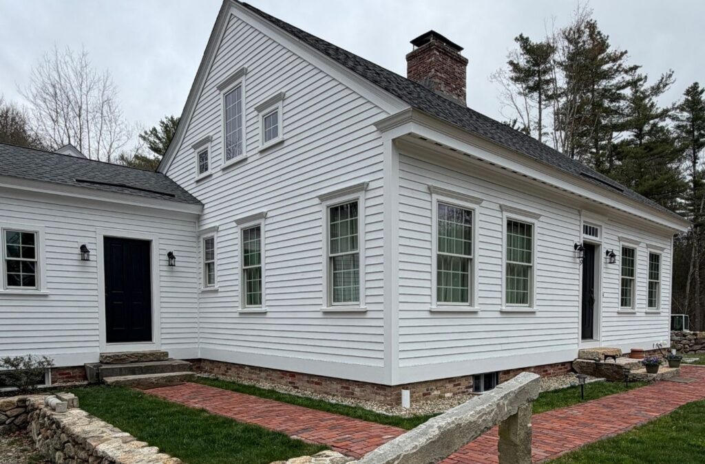 Experienced exterior painter inspecting siding seams and trim before applying finish coats
