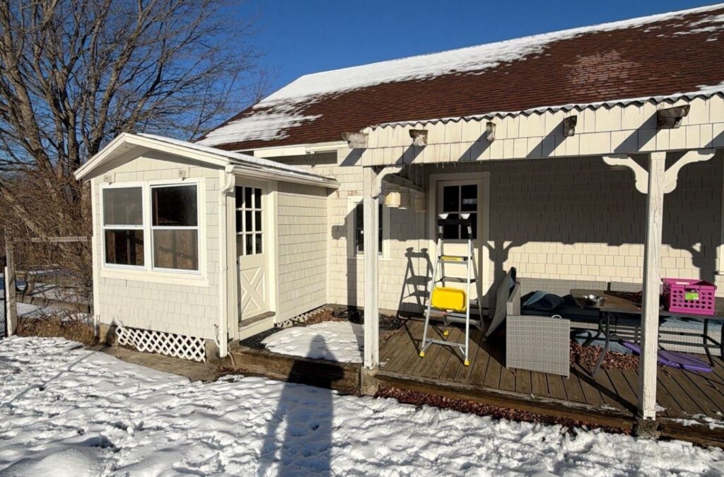 Painter preparing peeling trim and siding on an Acton home before exterior repainting