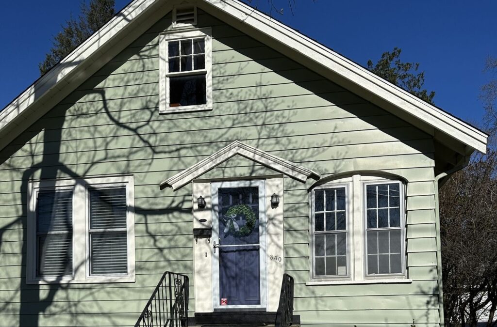 Painter preparing weathered siding and trim on a Holliston home before repainting