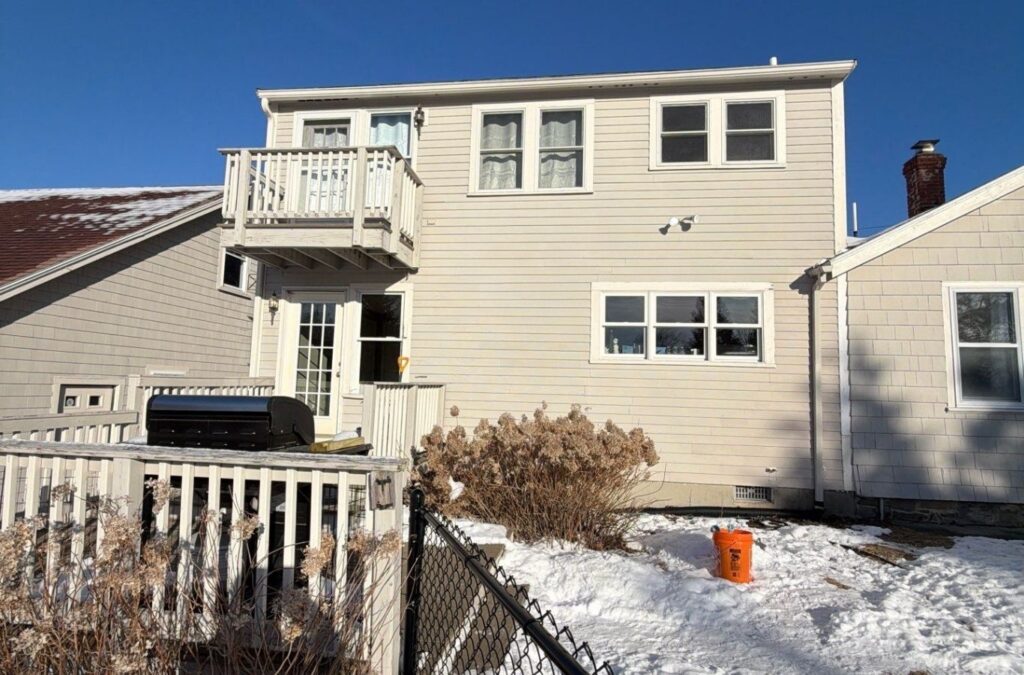 Painter inspecting weathered fascia boards and siding before detailed exterior repainting work