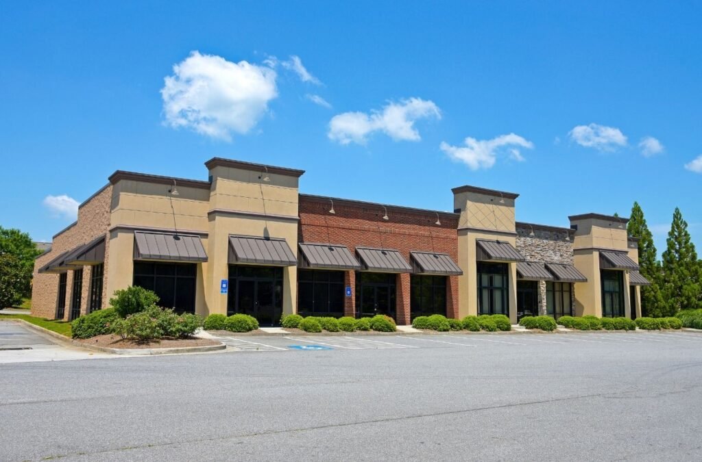 Tan and brick shopping plaza with metal awnings, a space suited to Lucena Painting commercial painting in Auburn, MA