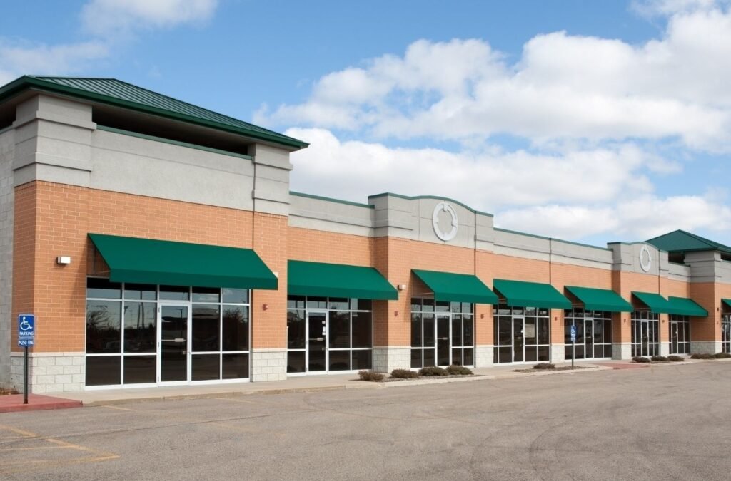Brick retail strip with green awnings, a building type for Lucena Painting commercial painting in Shrewsbury, MA